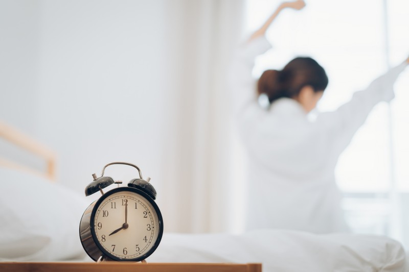 close-up-alarm-clock-table-with-woman-stretching-bed-background.jpg
